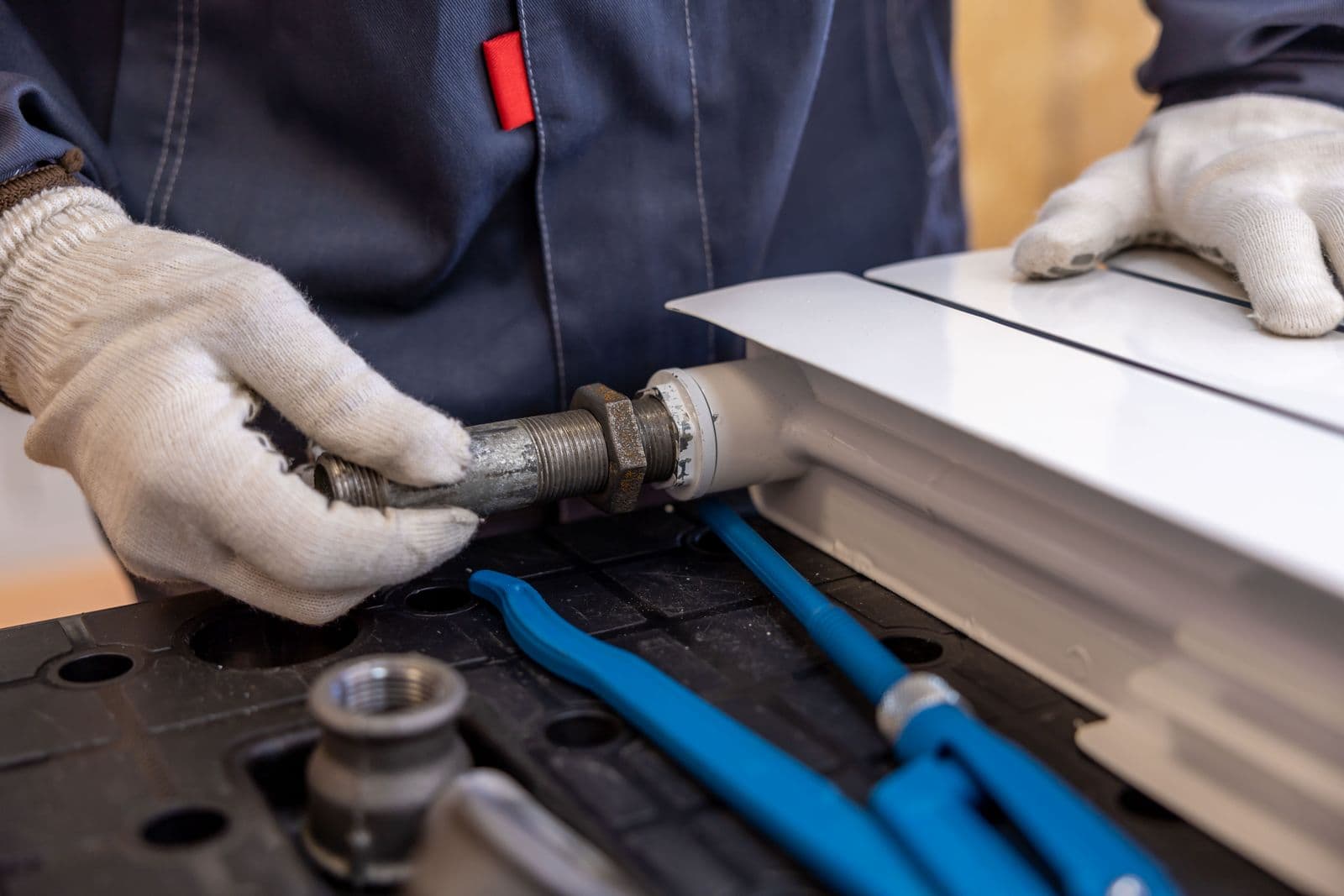 A plumber fitting a valve onto a radiator pipe